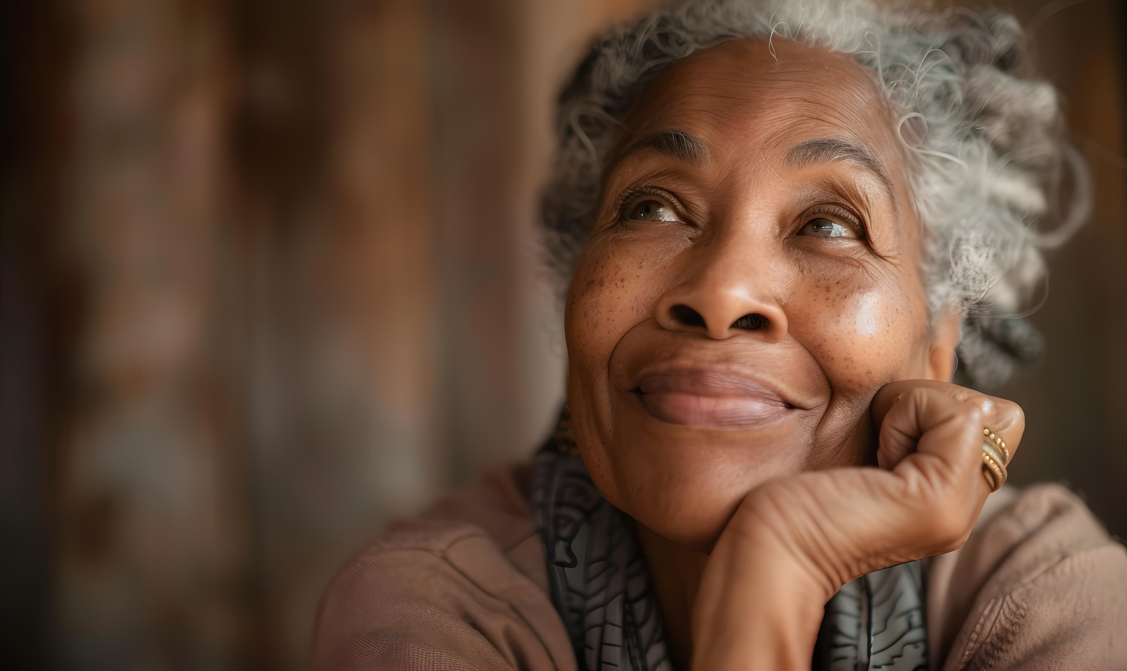 An older woman smiling softly, looking up with hope