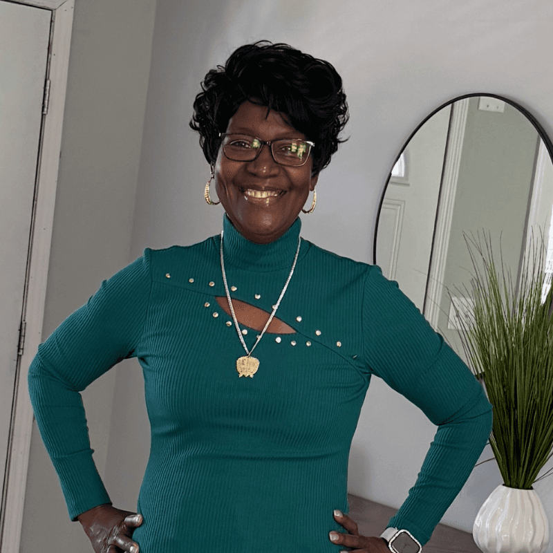 Debbie, smiling in her green top and gold jewelry — the reason ExpressAgain exists